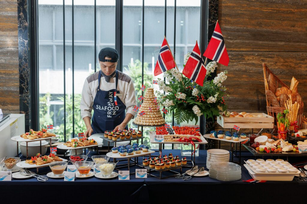 pexels-photo-32611696-32611696 A chef arranges a luxurious buffet with Nordic flags and diverse gourmet dishes indoors.