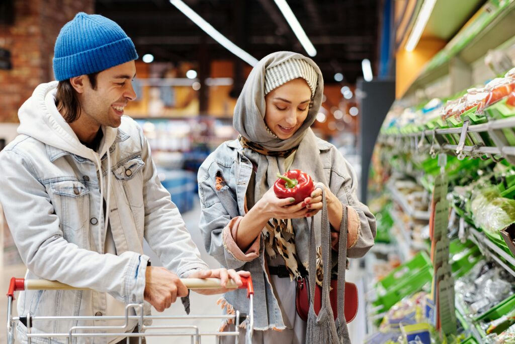 A happy couple shopping in a supermarket, selecting fresh bell peppers.